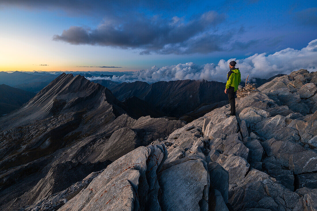 A trekker observes Crete de la Taillante from Pain de Sucre during dusk at summer, Pain de Sucre, Col Agnel, Alpi Cozie, Cuneo, Provance, Piedmont, France, Italy, Southern Europe