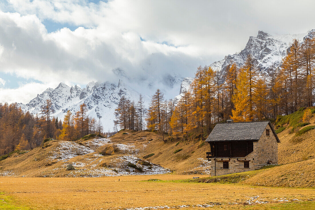 Herbstliche Ansicht einer Berghütte in der Ortschaft Crampiolo mit den Bergen, die die Alpe Devero umgeben. Alpe Devero, Devero-Tal, Antigorio-Tal, Ossola-Tal, Piemont, Gemeinde Verbano Cusio Ossola, Italien.