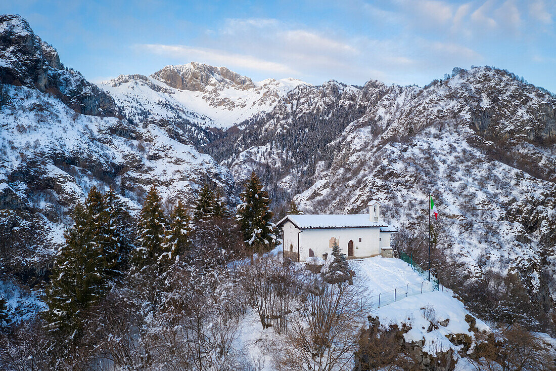 Luftaufnahme der kleinen Kirche San Peder und der Presolana während eines Wintersonnenuntergangs. Rusio, Castione della Presolana, Val Seriana, Bezirk Bergamo, Lombardei, Italien.