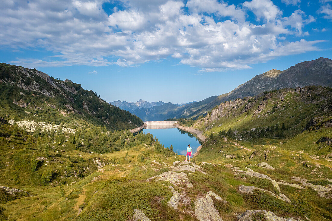 Summer view of a girl trekker admiring Lago di Fregabolgia. Carona, Val Brembana, Alpi Orobie, Bergamo, Bergamo Province, Lombardy, Italy, Europe.