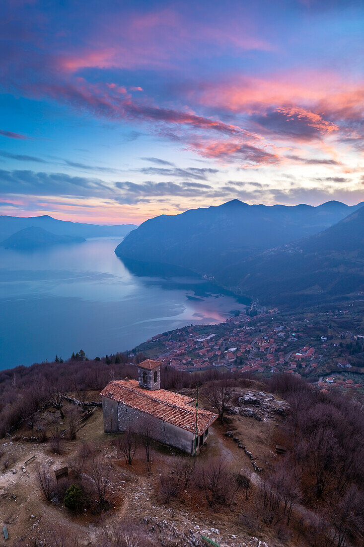 Aerial view of the small church of San Defendente dominating Lake Iseo at sunset. Solto Collina, Iseo Lake, Bergamo district, Lombardy, Italy.