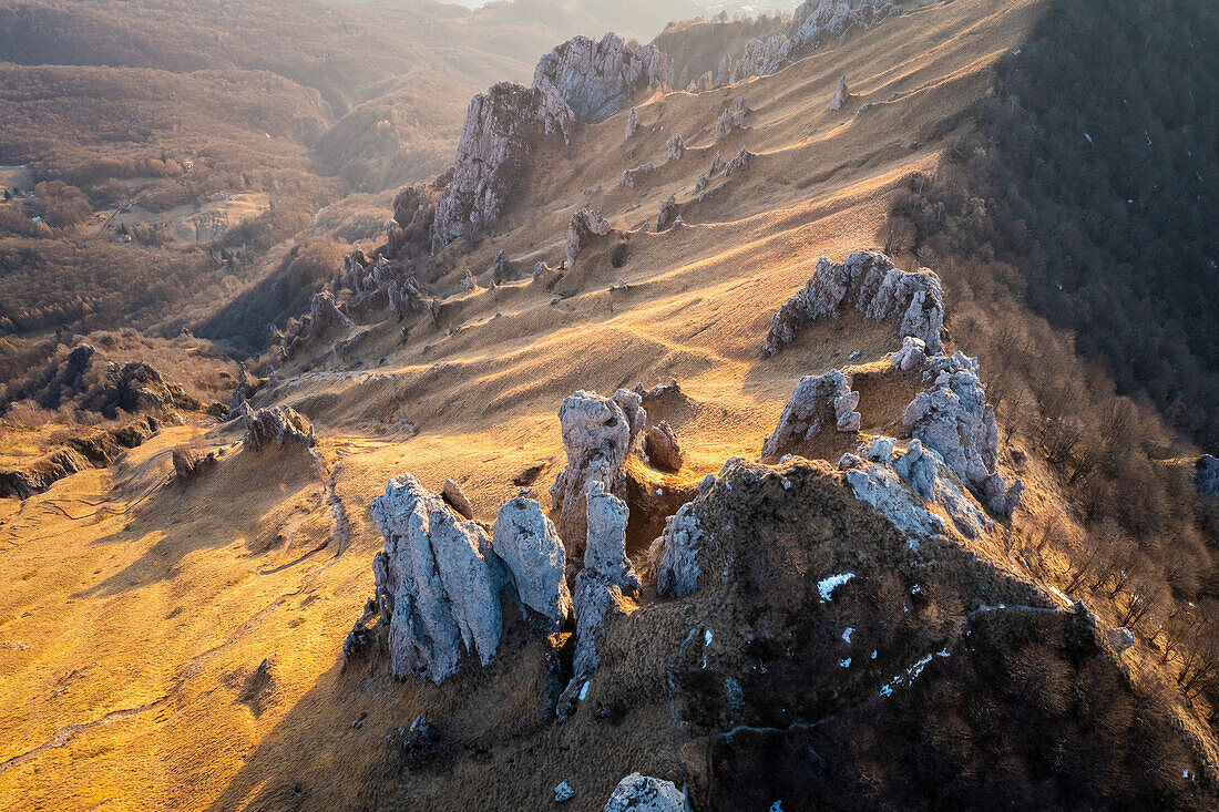 Aerial view of the side of Colle Pertusio and the valley below Rifugio Rosalba with it's rock formations at sunset. Piani Resinelli, Lecco, Lombardy, Italy.