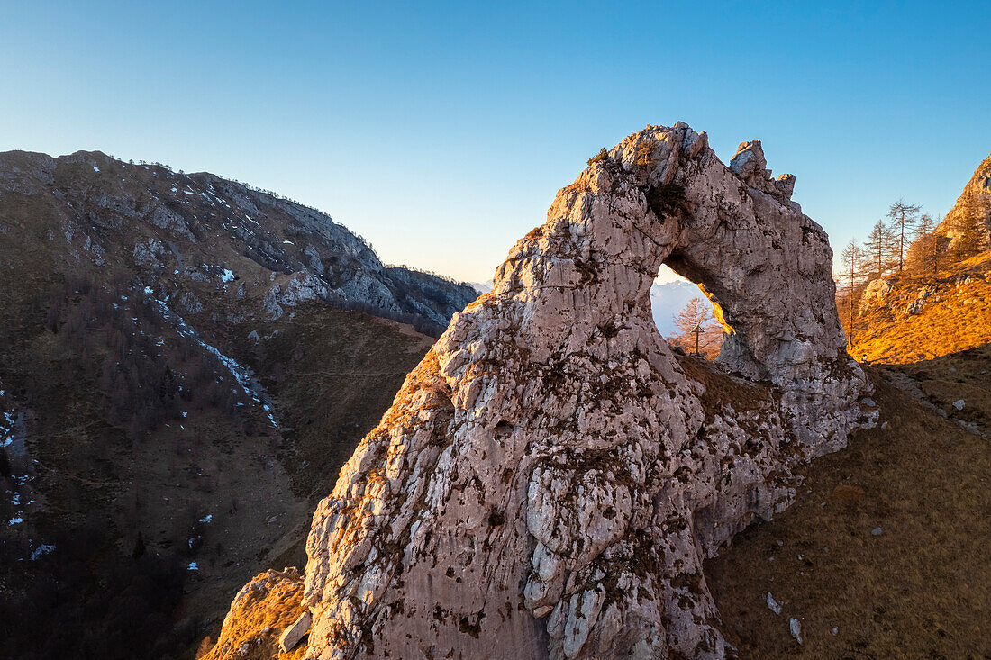 Aerial view of the natural arch rock formation called Porta di Prada in the Grigna mountain at sunset. Grigna Settentrionale (Grignone), Mandello del Lario, Lombardy, Italy.