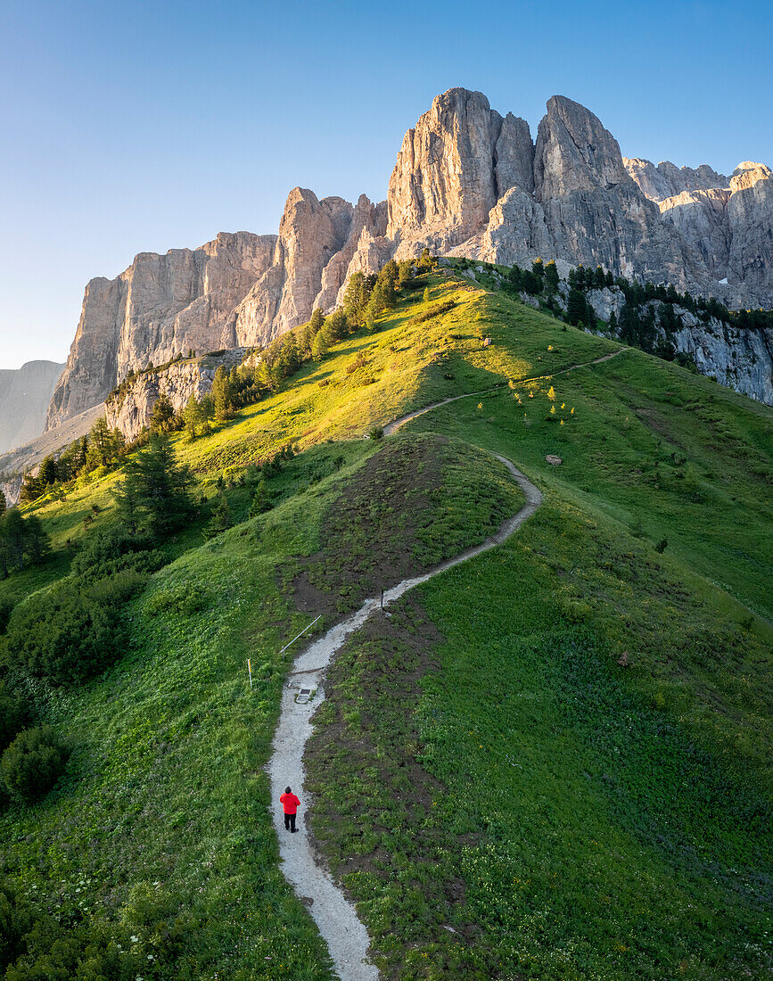 Aerial view of a person admiring the Gardena Pass at sunrise. Dolomites, South Tyrol, Bolzano district, Italy, Europe.