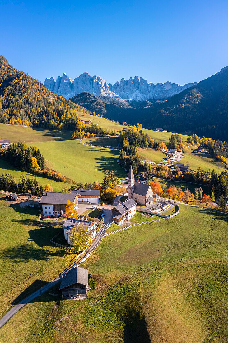 Luftaufnahme der Kirche von Santa Maddalena mit der Geislergruppe im Hintergrund. St. Magdalena im Pustertal, Pustertal, Bozen, Südtirol, Trentino Südtirol, Italien.