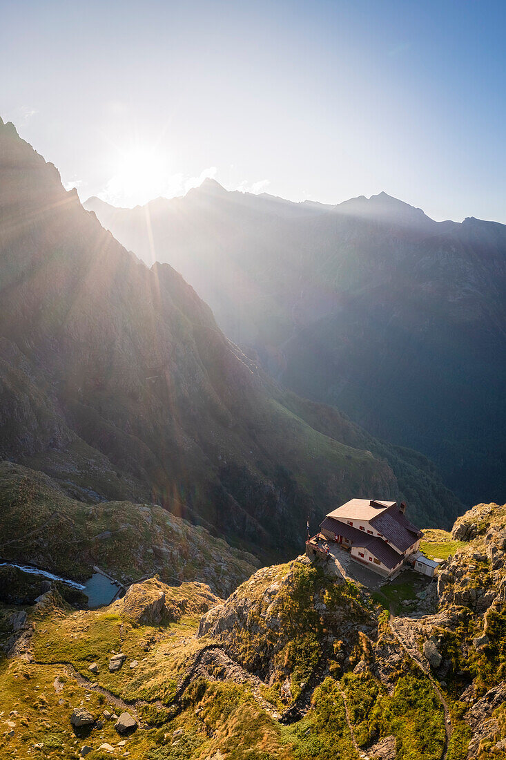 Luftaufnahme des Rifugio Merelli al Coca auf einer Klippe über der Stadt Valbondione. Valbondione, Seriana-Tal, Lombardei, Provinz Bergamo, Italien.