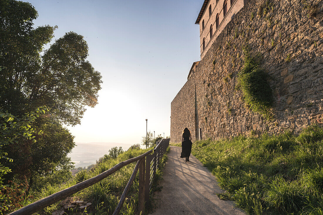 A young woman walking into a panoramic path in Volterra, Pisa province, Tuscany, Italy, Europe