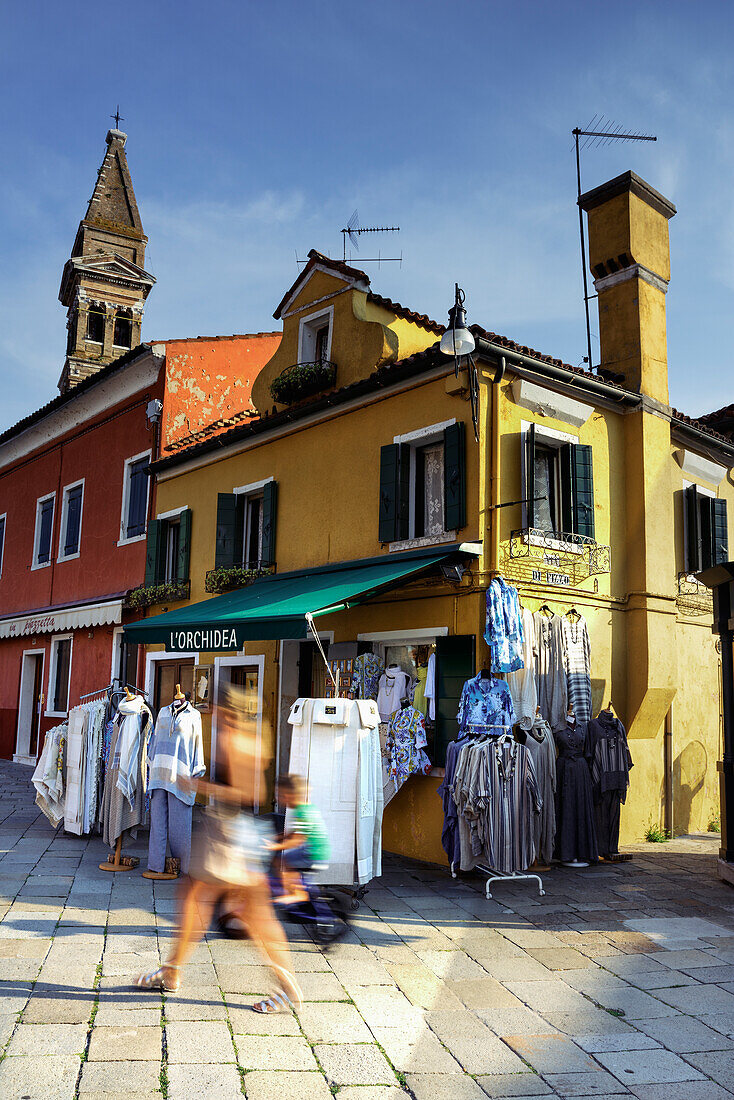 Burano, typischer Handwerkerladen mit Touristen und Blick auf den schiefen Glockenturm; Burano, Veneto, Italia, Italien, Europa, Südeuropa