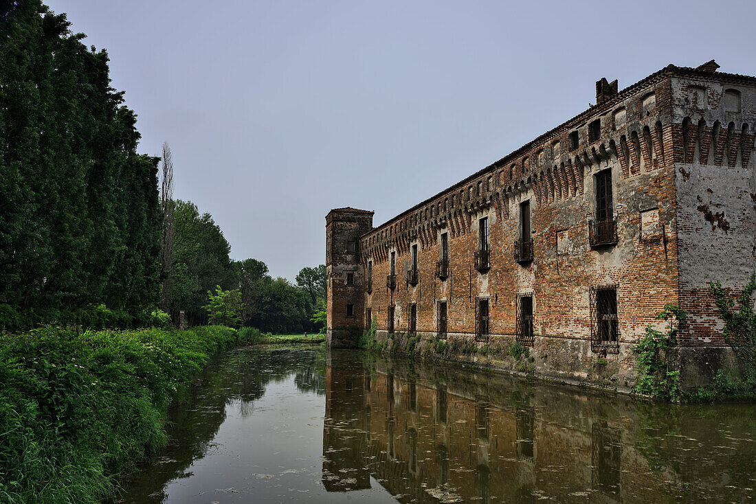 Detail des Wassergrabens der Burg Padernello mit Spiegelungen im Vordergrund und Bäumen mit Vegetation, Padernello, Brescia, Lombardei, Italien
