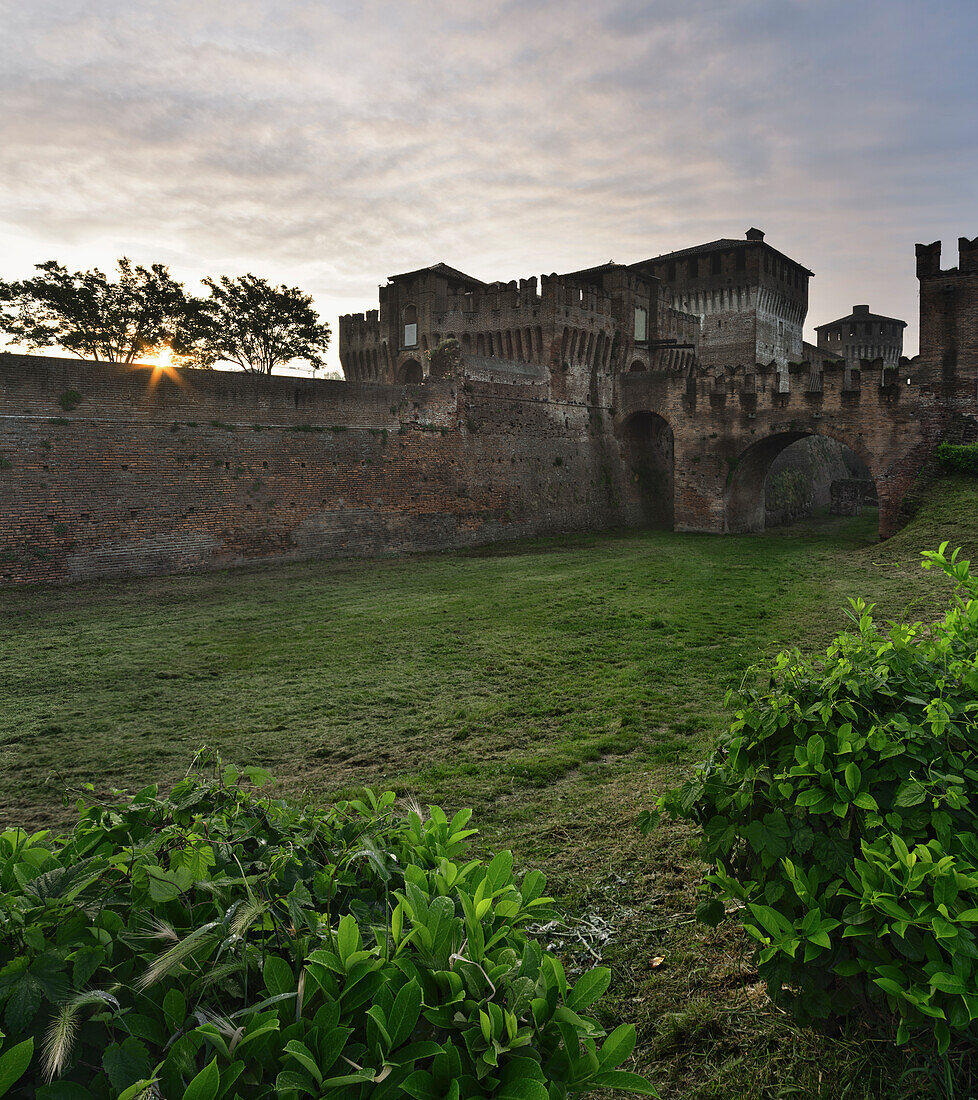 Schloss von Soncino, Seiteneingang mit Brücke, Vegetation und erste Sonne im Sonnenaufgang, Soncino, Provinz Cremona, Lombardei, Italien, Europa