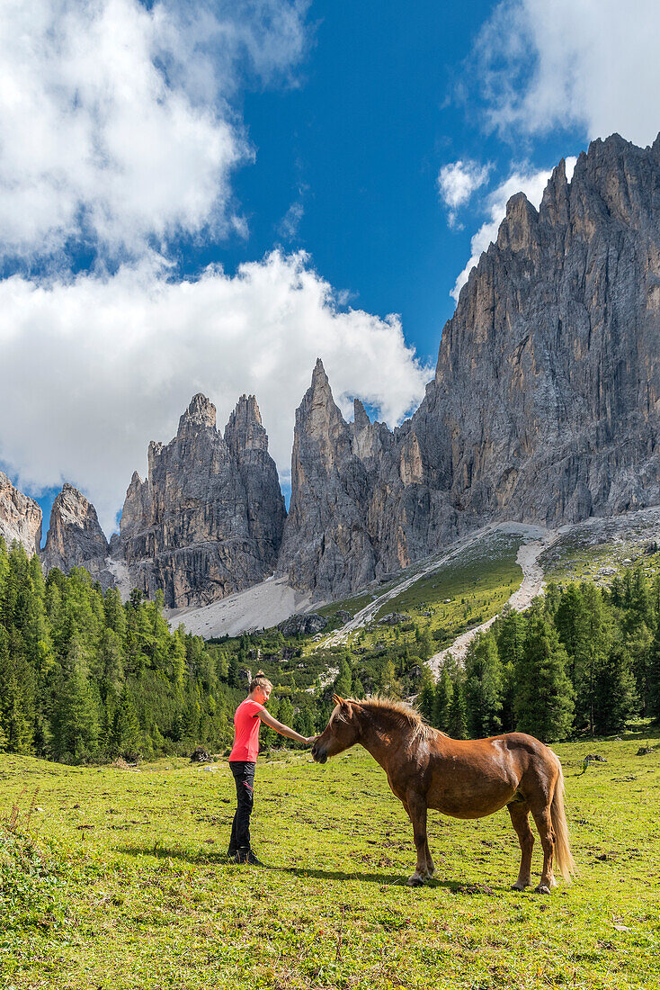 Tiers / Tires, Tires Valley, province of Bolzano, Dolomites, South Tyrol, Italy. A girl strokes a horse in front of the Vaiolet Towers