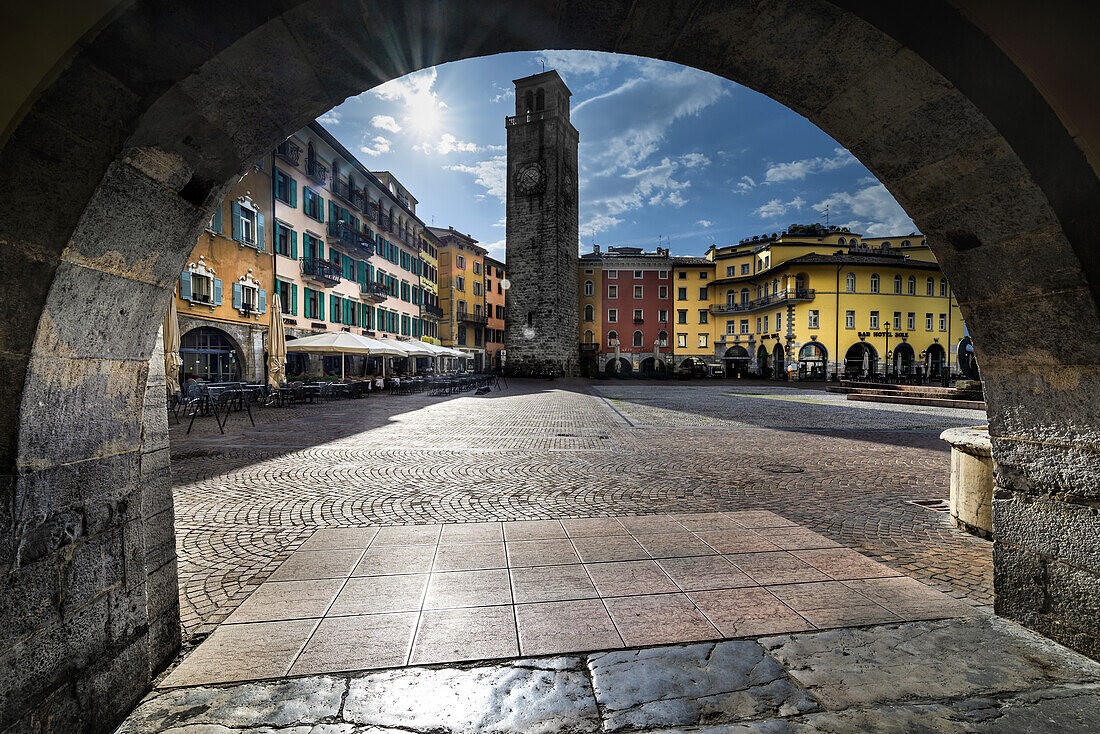 3 november square in Riva del Garda, with typical houses of the center and Apponale tower in background, with frontal sun during the early morning. Riva del Garda, Trentino alto adige, province of Trento, north Italy, south Europe