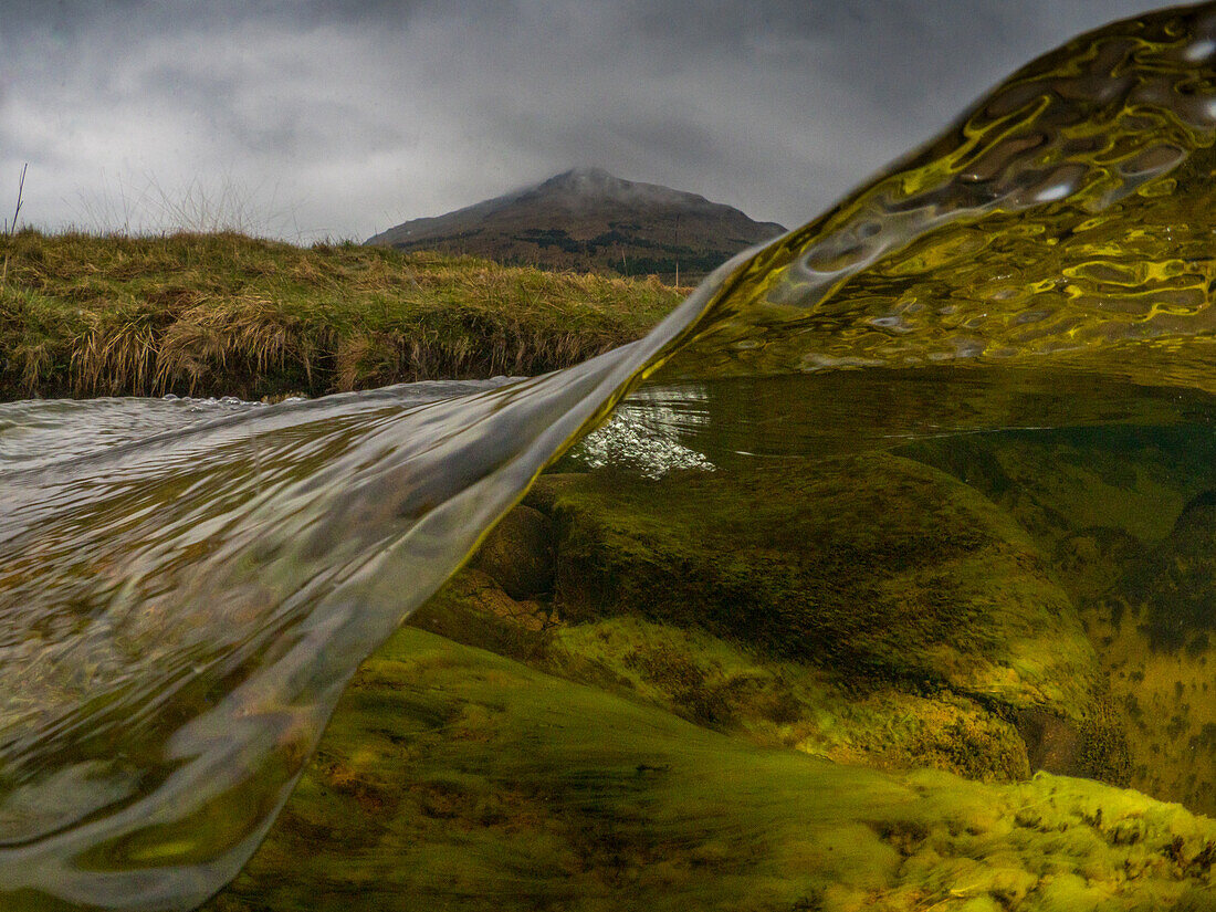 Split shot of the river kinglas with hills in the background. Algae is visible under the water. Scotland.
