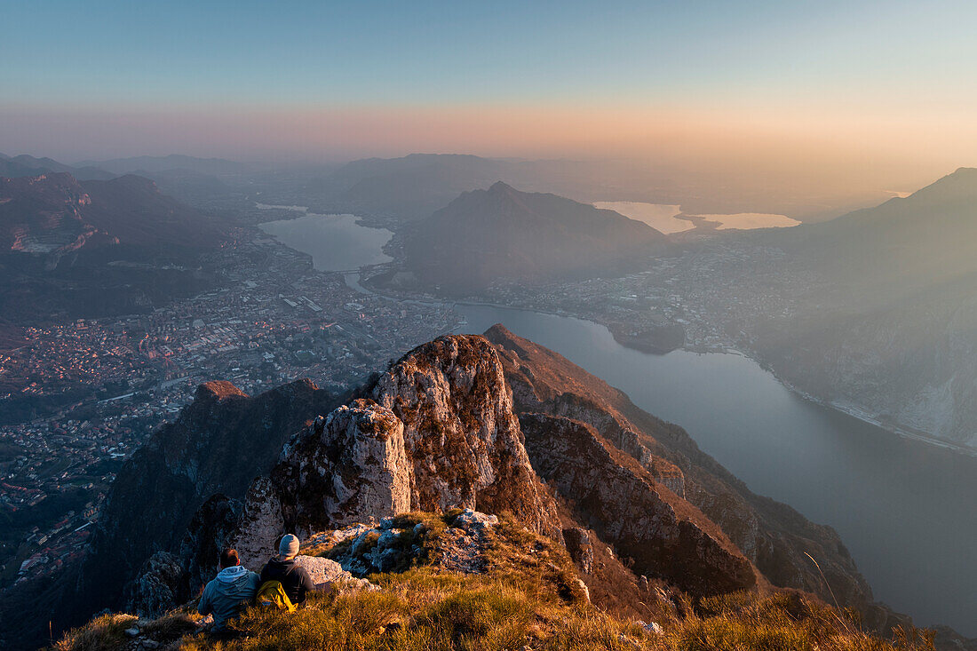 Zwei Freunde beobachten den Sonnenuntergang vom Gipfel des Monte Coltiglione, Provinz Lecco, Lombardei, Italien, Europa