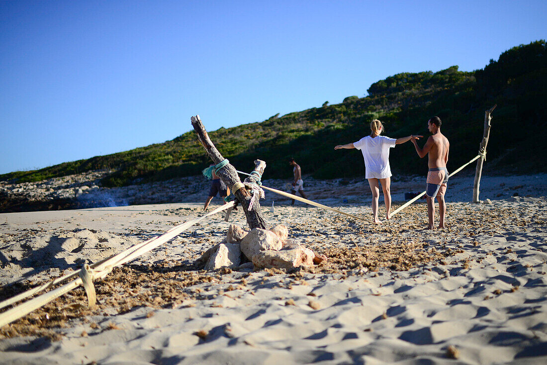 Mann bringt Frau Slackline bei in Cala Varques auf Mallorca, Spanien