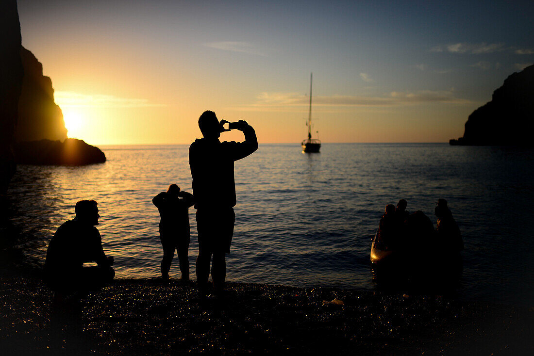 Eine Gruppe von Menschen genießt den Sonnenuntergang in Torrent de Pareis, Mallorca, Spanien