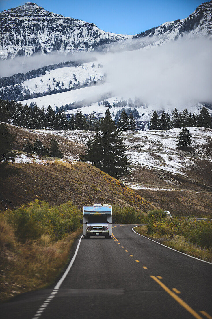 Camper van in road among winter landscape, Yellowstone National Park, USA