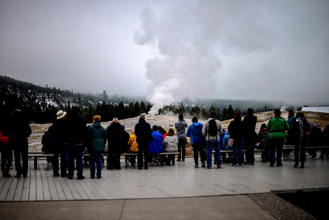 Besucher beobachten den Ausbruch des Geysirs Old Faithful im Upper Geyser Basin, Yellowstone-Nationalpark, USA
