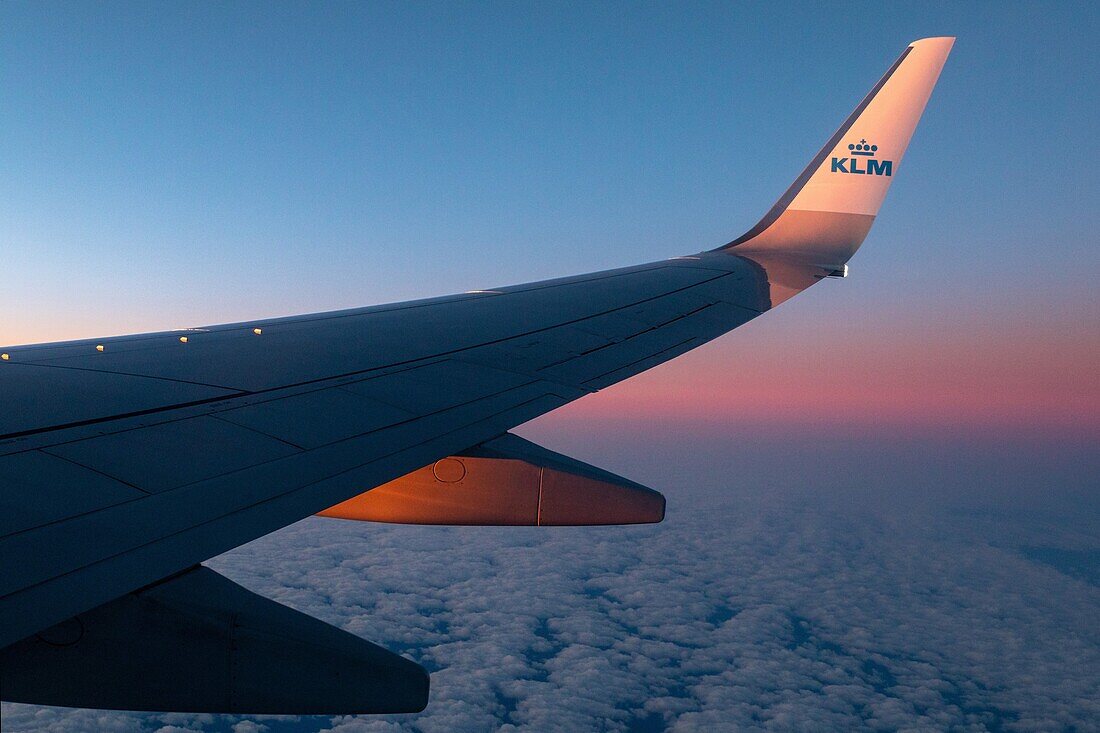 Flügel eines Flugzeugs von klm airlines bei Sonnenuntergang über einem bewölkten Himmel