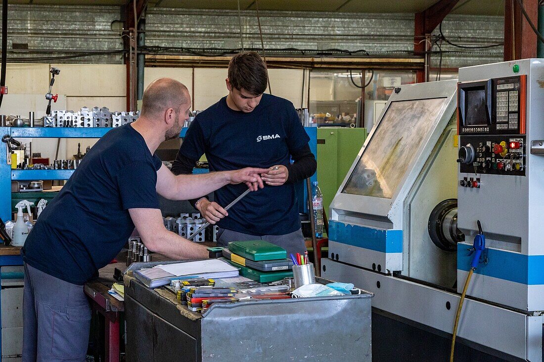 Worker with his apprentice passing on instructions and training in the use of the equipment, sma, societe mecanique aiglonne, metallurgical industry, saint-martin-d'ecublei, orne, normandy, france