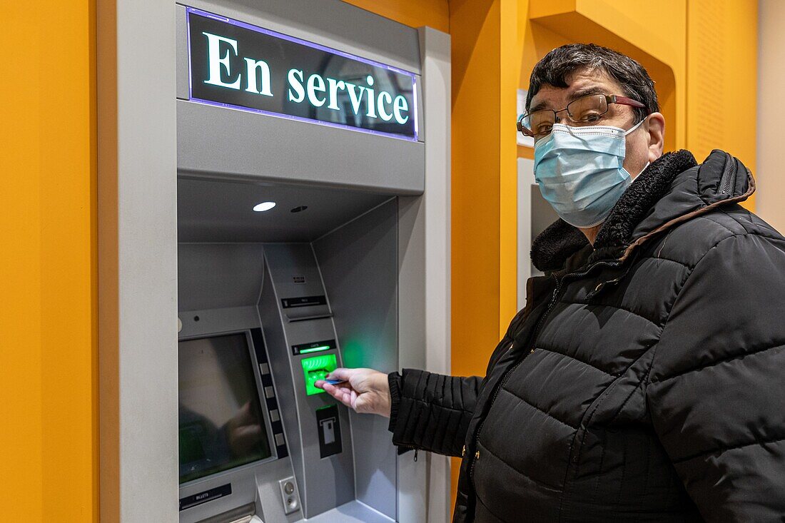Autonomous resident in front of an atm, adults with moderate mental disabilities, residence du moulin de la risle, rugles, eure, normandy, france