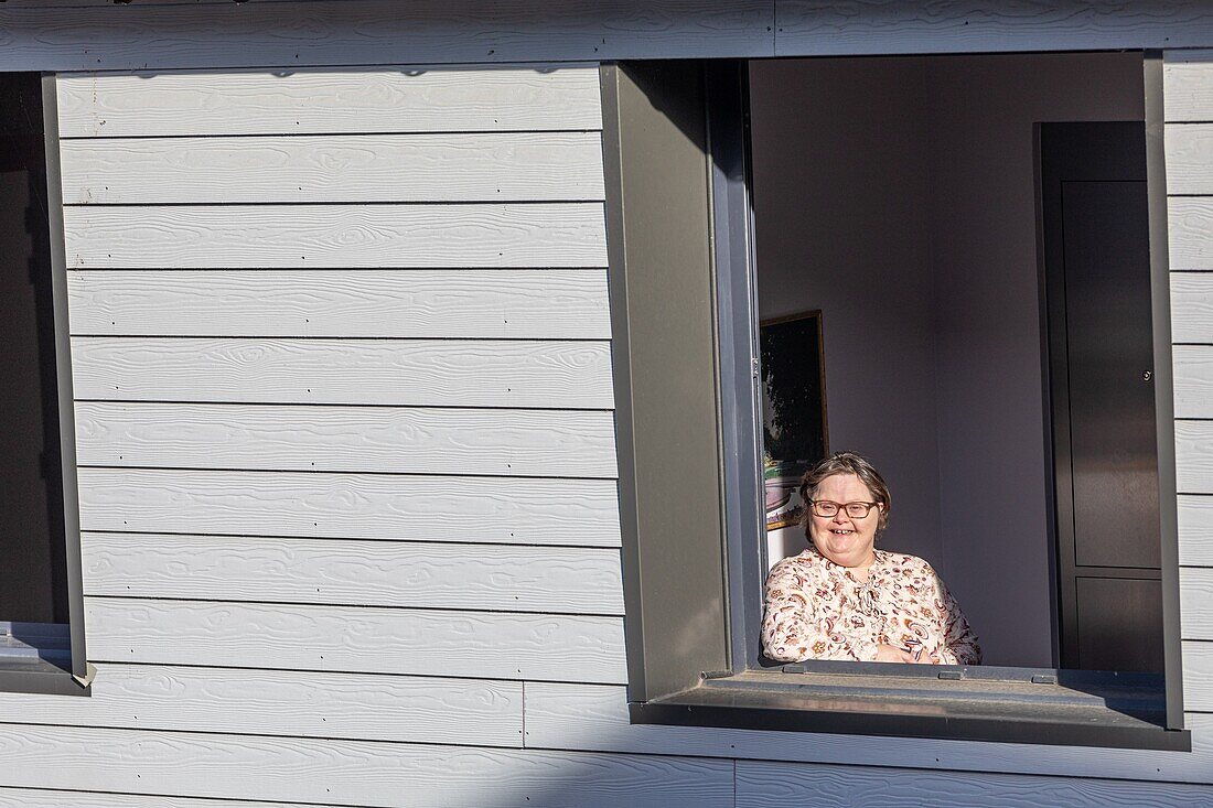 Resident at the window of her individual room, care home for adults with mental disabilities, residence la charentonne, adapei27, association departementale d'amis et de parents, bernay, eure, normandy, france