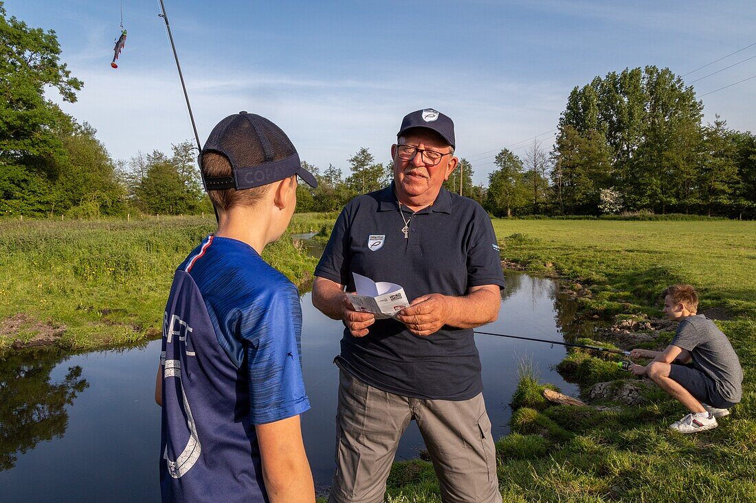 Water bailiff checking the permits of young fishers on the iton river, cintray, iton river valley, eure, normandy, france