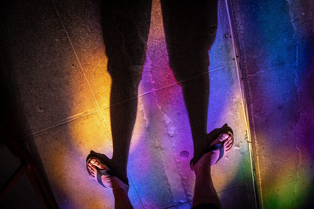 Reflections of the stained glass on the floor and feet, saint-sauveur abbey church, aniane, herault, occitanie, france