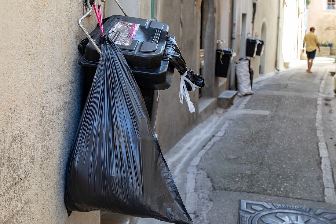 An den Wänden hängender Müllsack auf der Straße, aniane, herault, occitanie, frankreich