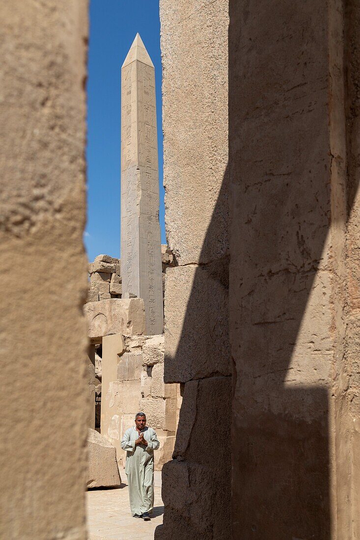 Mann in einer Djellaba vor einem Obelisken im Bezirk von Amun-Re, Tempel von Karnak, antike ägyptische Stätte aus der 13. Dynastie, unesco-Weltkulturerbe, Luxor, Ägypten, Afrika