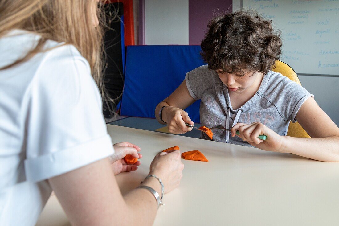 Ergotherapy session with a resident to teach her how to use a knife and fork, sessad la rencontre, day care, support and service organization for people with disabilities, le neubourg, eure, normandy, france