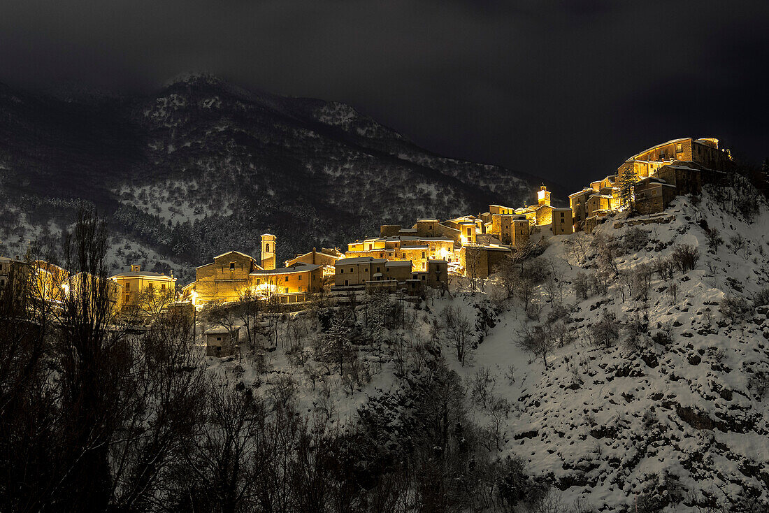 Nachtansicht des beleuchteten, schneebedeckten Dorfes Villalago, Nationalpark Abruzzen, Provinz L'aquila, Abruzzen, Italien