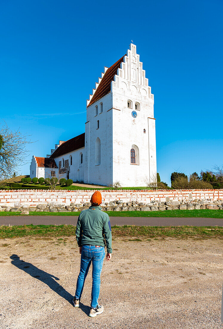 Man admiring the ancient danish styled facade of the church in Elmelunde village, Mon Island, Zealand, Denmark, Europe