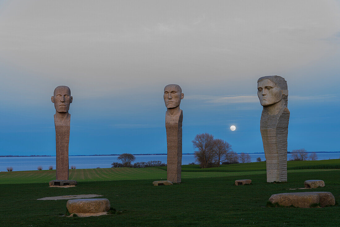 Detail der Köpfe der drei Steinstatuen von Dodekalitten bei aufgehendem Vollmond in der Abenddämmerung, Insel Lolland, Seeland, Dänemark, Europa