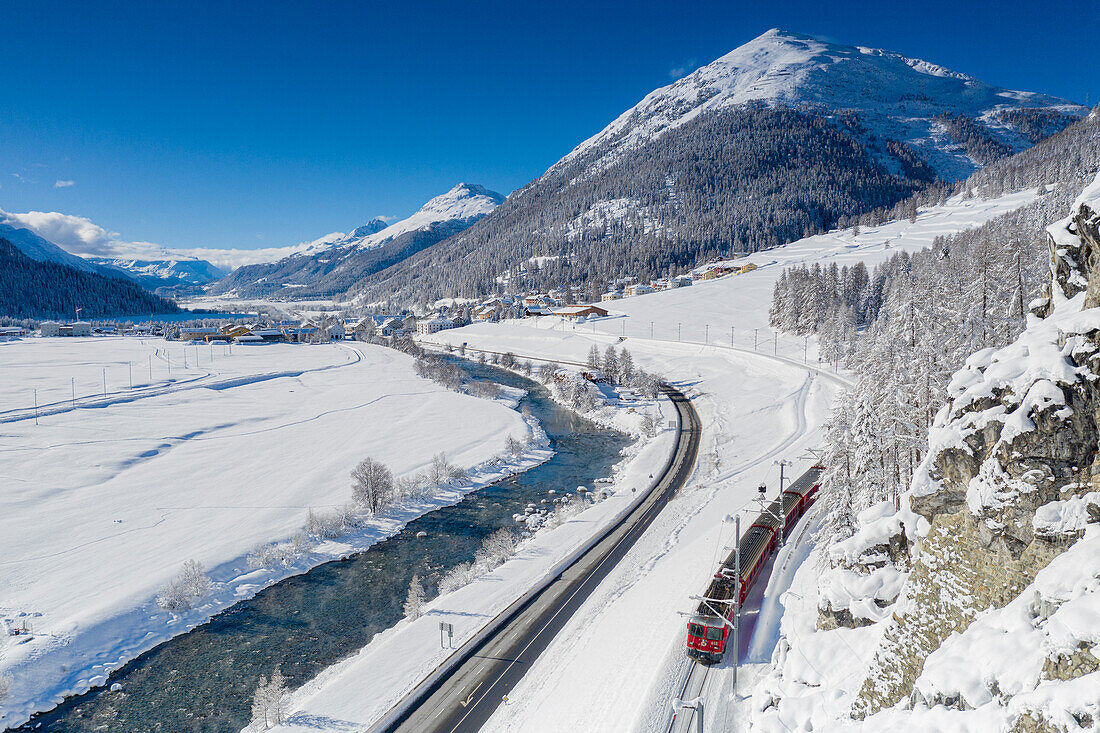 Bernina Express Zug in der verschneiten Landschaft am Innufer, Madulain, Graubünden, Engadin, Schweiz