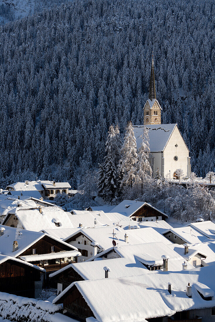 Die Kirche San Geer und die mit Schnee bedeckten Dächer im Dorf Scuol, Graubünden, Engadin, Schweiz