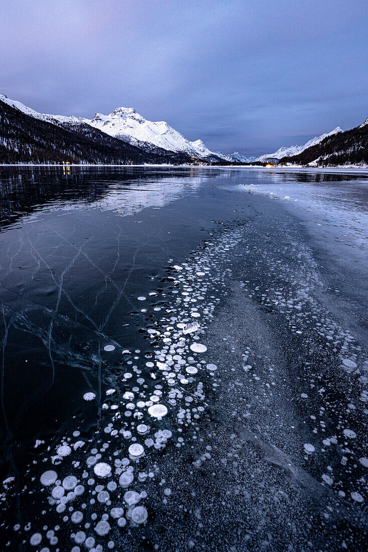 Methane gas bubbles trapped in ice on frozen Lake Silvaplana at night, Maloja, Engadine, Graubunden canton, Switzerland