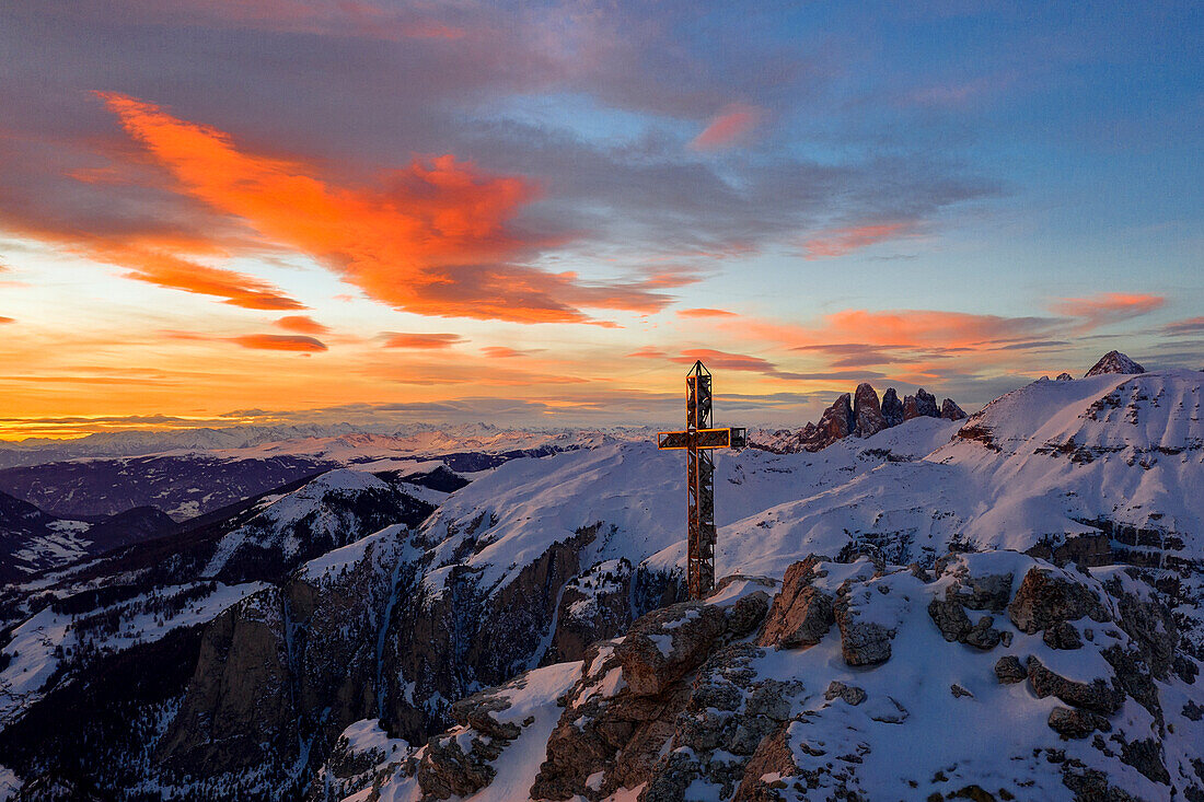 Brennender Himmel bei Sonnenuntergang über dem Gipfelkreuz des Gran Cir und den Geislerspitzen im Hintergrund, Dolomiten, Südtirol, Italien