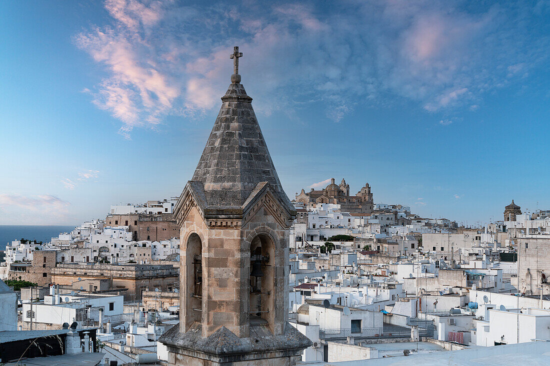 Ancient bell tower and whitewashed houses of Ostuni old town at sunset, province of Brindisi, Salento, Apulia, Italy