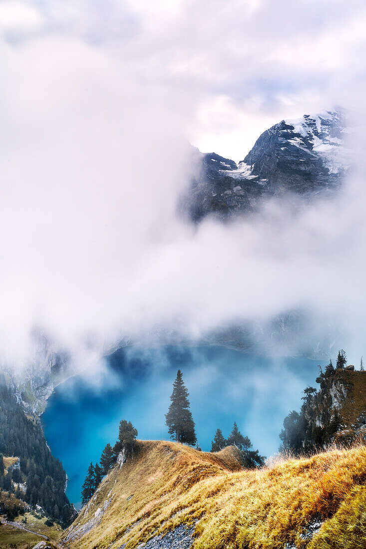 Pristine lake Oeschinensee and mountains in the mist, Bernese Oberland, Kandersteg, canton of Bern, Switzerland