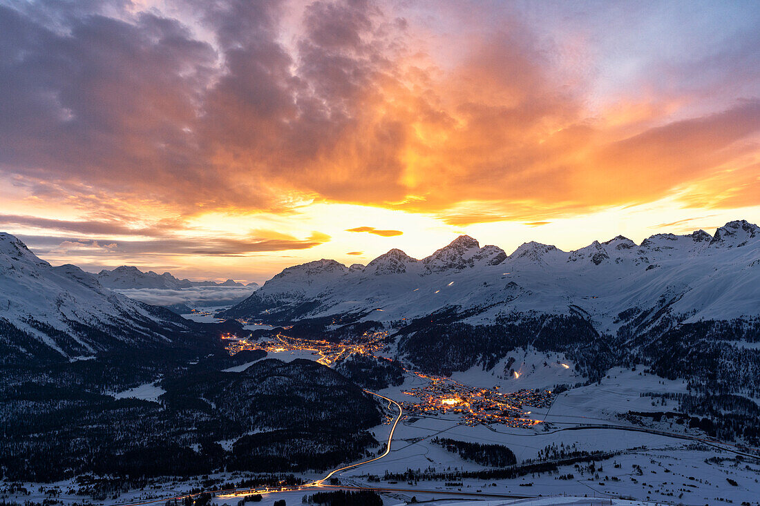 Brennender Himmel bei Sonnenuntergang über den verschneiten Alpendörfern von St. Moritz und Celerina, Engadin, Graubünden, Schweiz