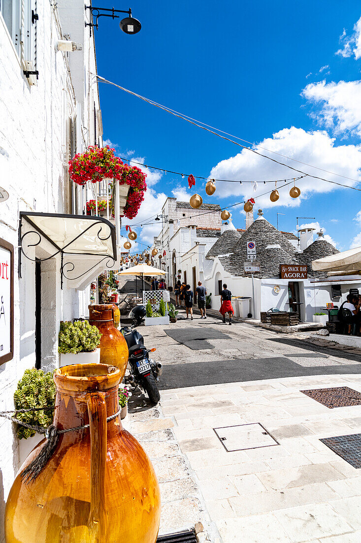 Tourists walking among the Trulli huts in the old alley of Alberobello, province of Bari, Apulia, Italy