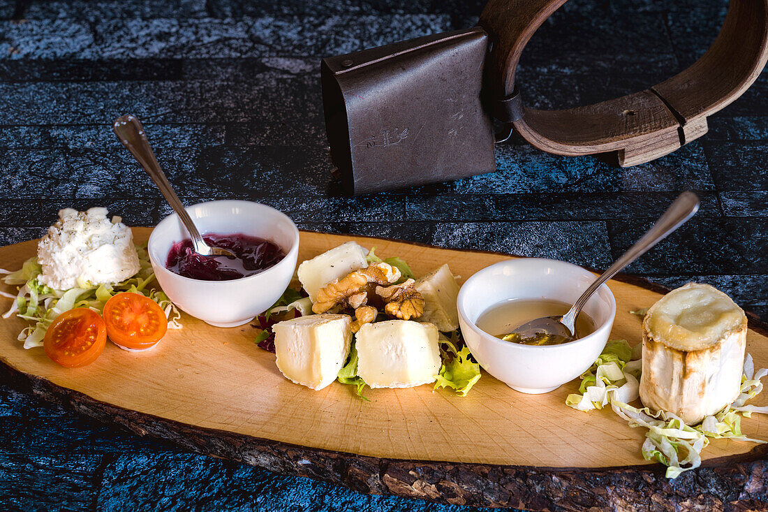 Goat cheese served with jam, honey and walnuts on wood chopping board, Italy