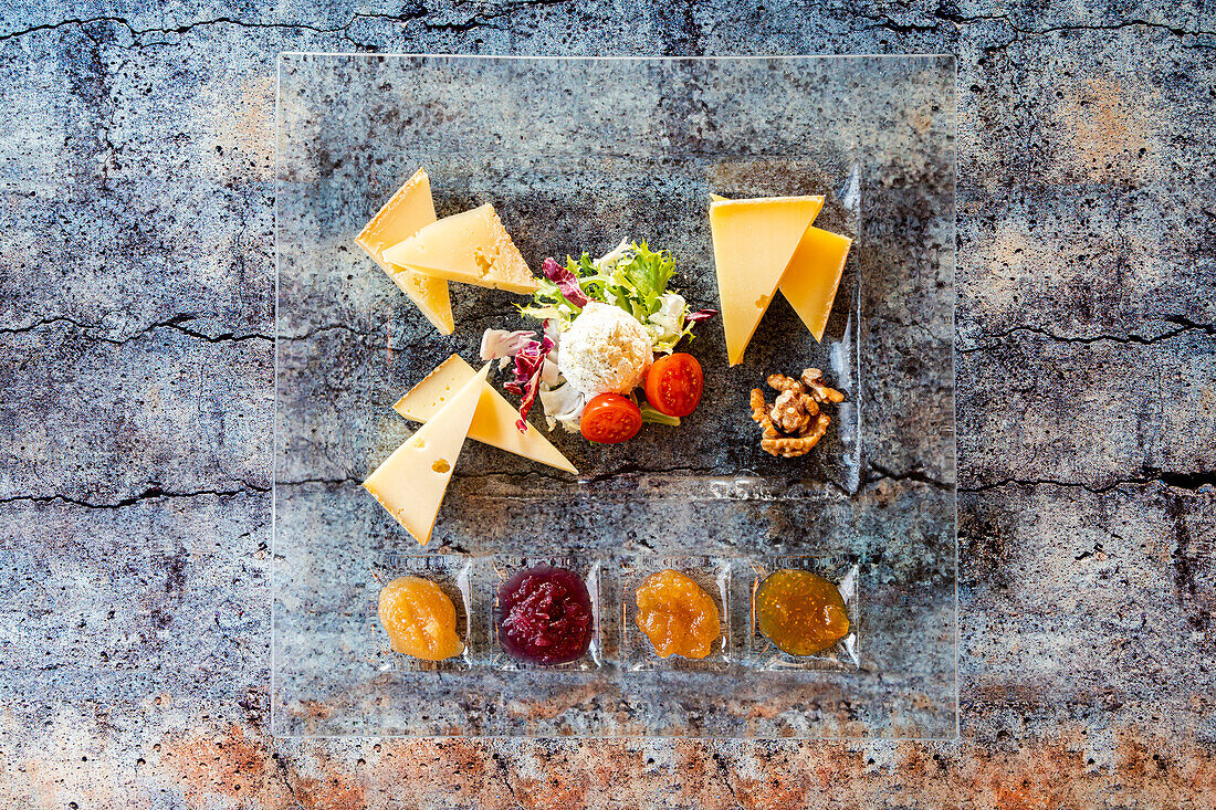 Selection of typical italian cheese served with jam in glass dish from above