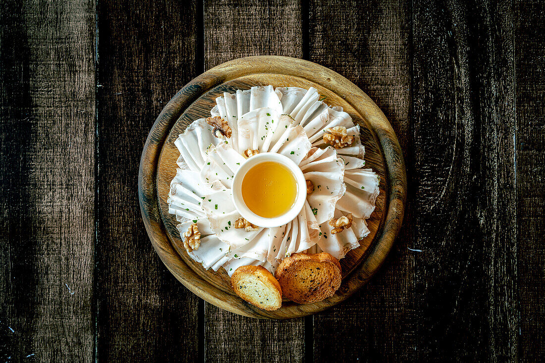 Chopping board with lard meat, walnuts and honey appetizer on wood table background from above, Italy