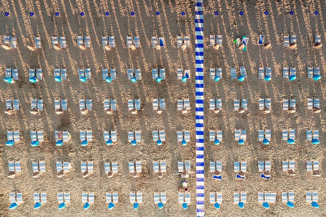 Aerial view of white sunbeds in a row on empty sand beach in summer, Vieste, Foggia province, Gargano, Apulia, Italy