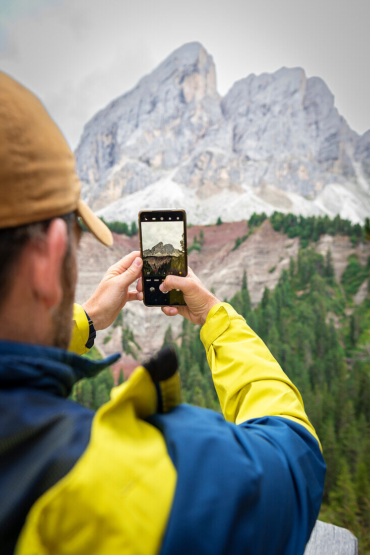 Rear view of a man photographing Sass de Putia with the smartphone, Passo delle Erbe, Dolomites, Puez Odle, Bolzano district, South Tyrol, Italy, Europe.