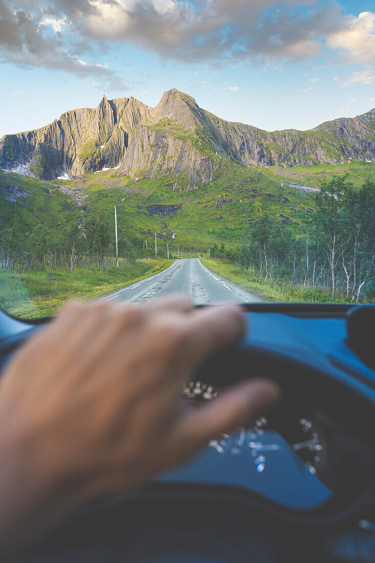 Persönliche Perspektive einer Person, die auf einer Straße in Richtung Berge in Senja, Provinz Troms, Norwegen, fährt