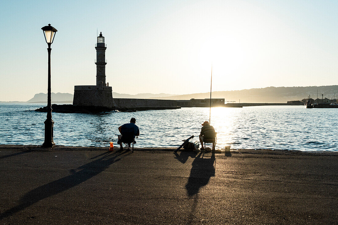 Fishermen in the old harbour of Chania at sunrise, island of Crete, Greece