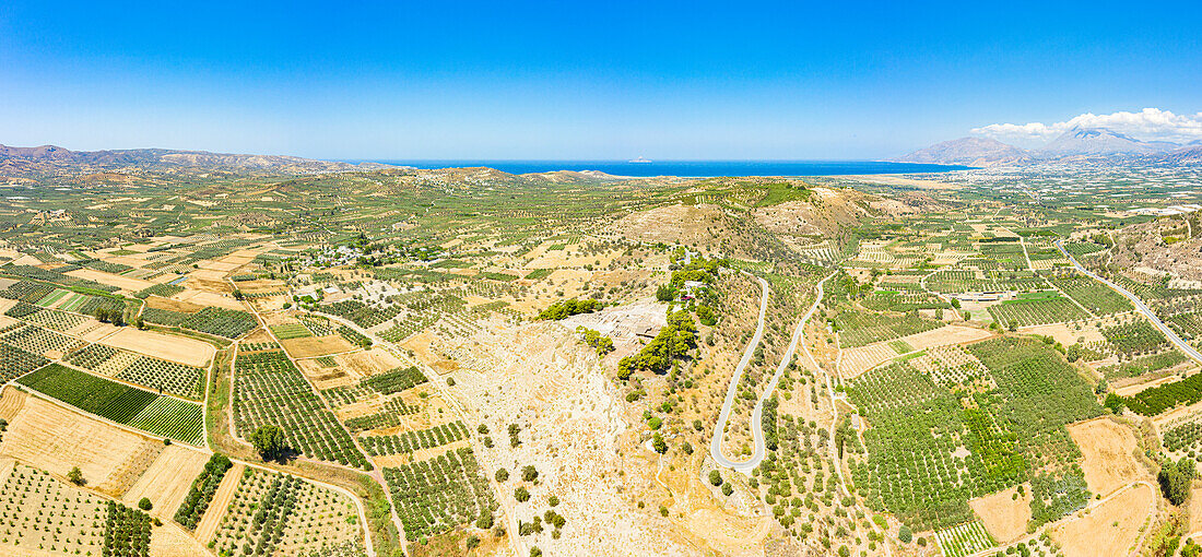 Aerial panoramic of Phaistos archeological site and olive groves with the blue sea on background, Crete, Greece